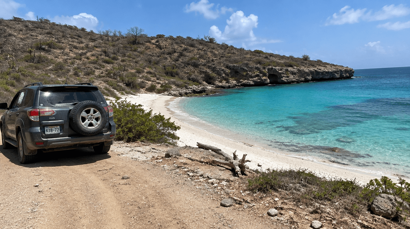 Verlaten baai op CuraƧao bereikt via een stoffige onverharde weg, met een robuuste SUV geparkeerd bij het turquoise water