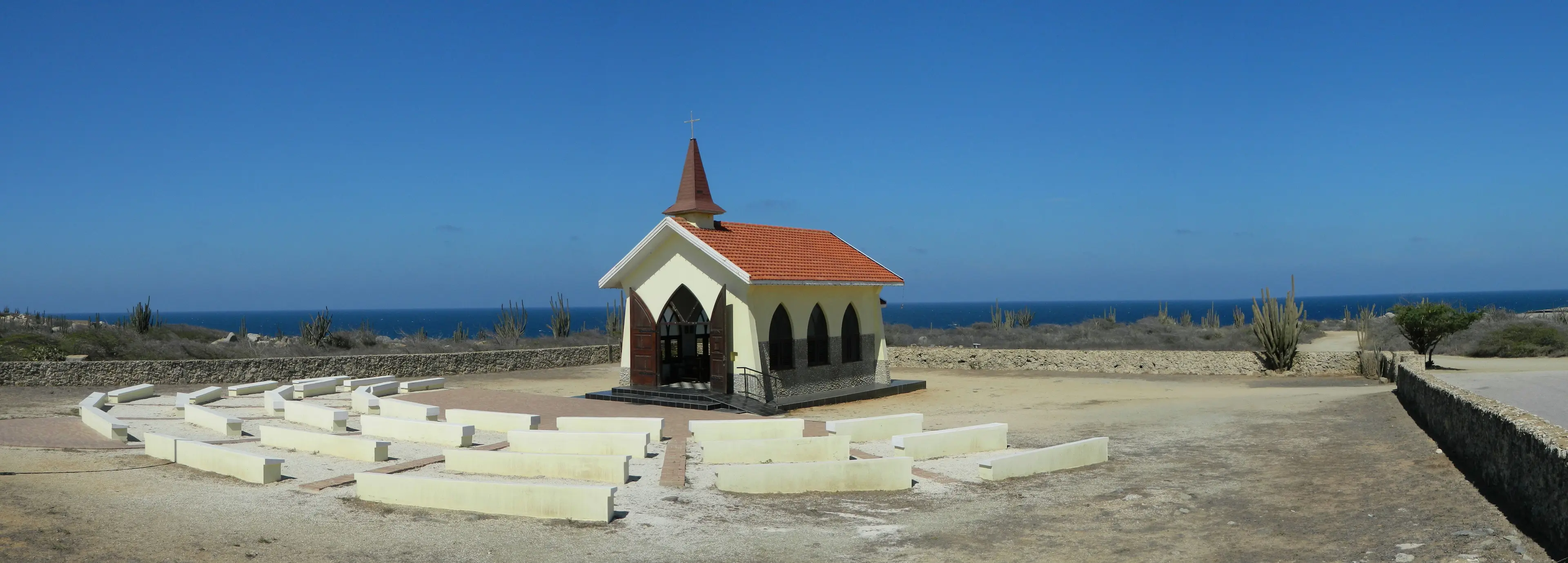 Capilla Alto Vista en Aruba, edificio amarillo con techo rojo contra un cielo azul intenso