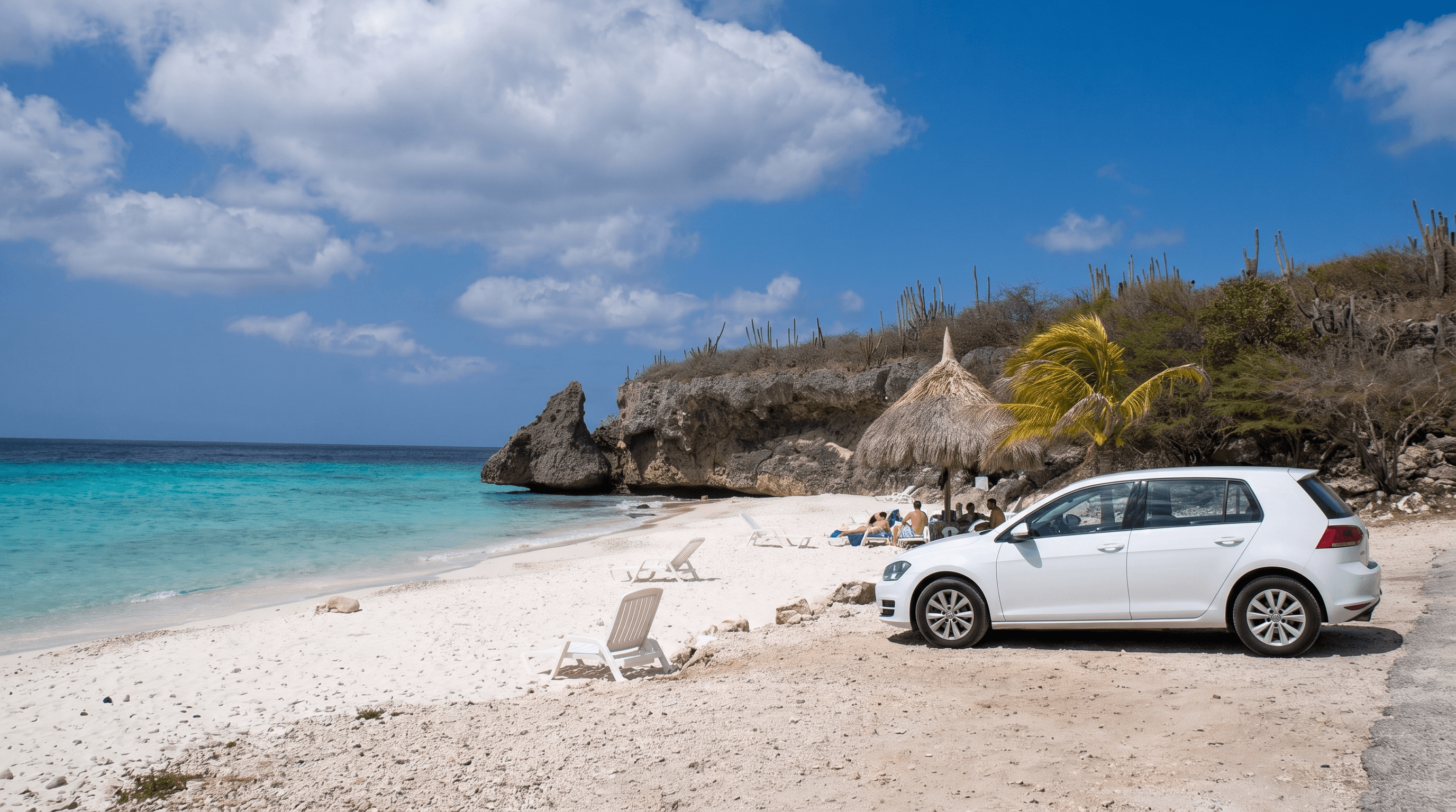 Witte huurauto geparkeerd bij Playa Cas Abao aan de westkust van Curaçao met turquoise water