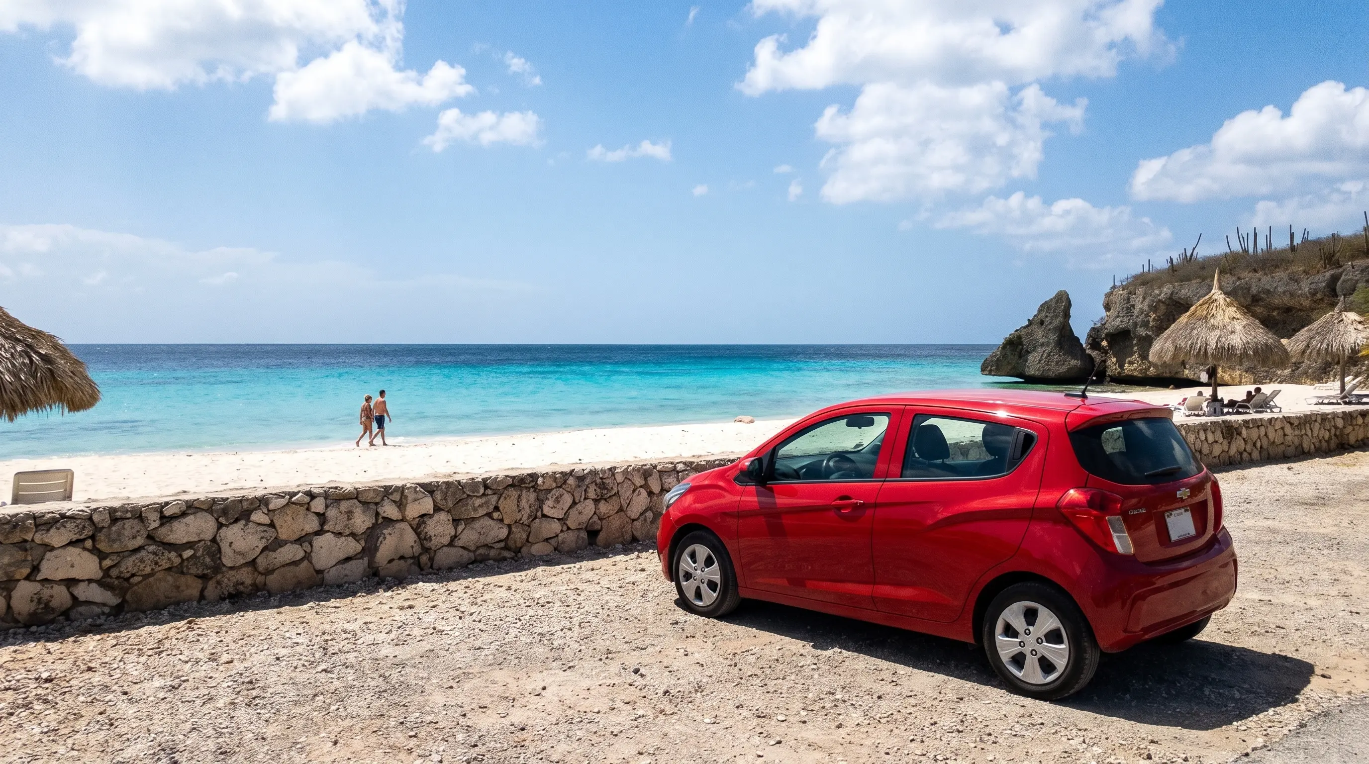 Kompakter roter Mietwagen parkt oberhalb des Strandes Cas Abao auf Curaçao mit türkisfarbenem Wasser im Hintergrund
